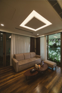 A living room with wooden floors and glass doors, lit by a fancy, warm lighting fixture