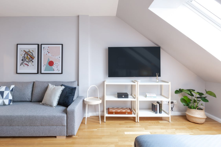 A staged home’s living room, with a grey sofa and white furniture