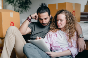 A man and woman are looking at a notebook surrounded by boxes